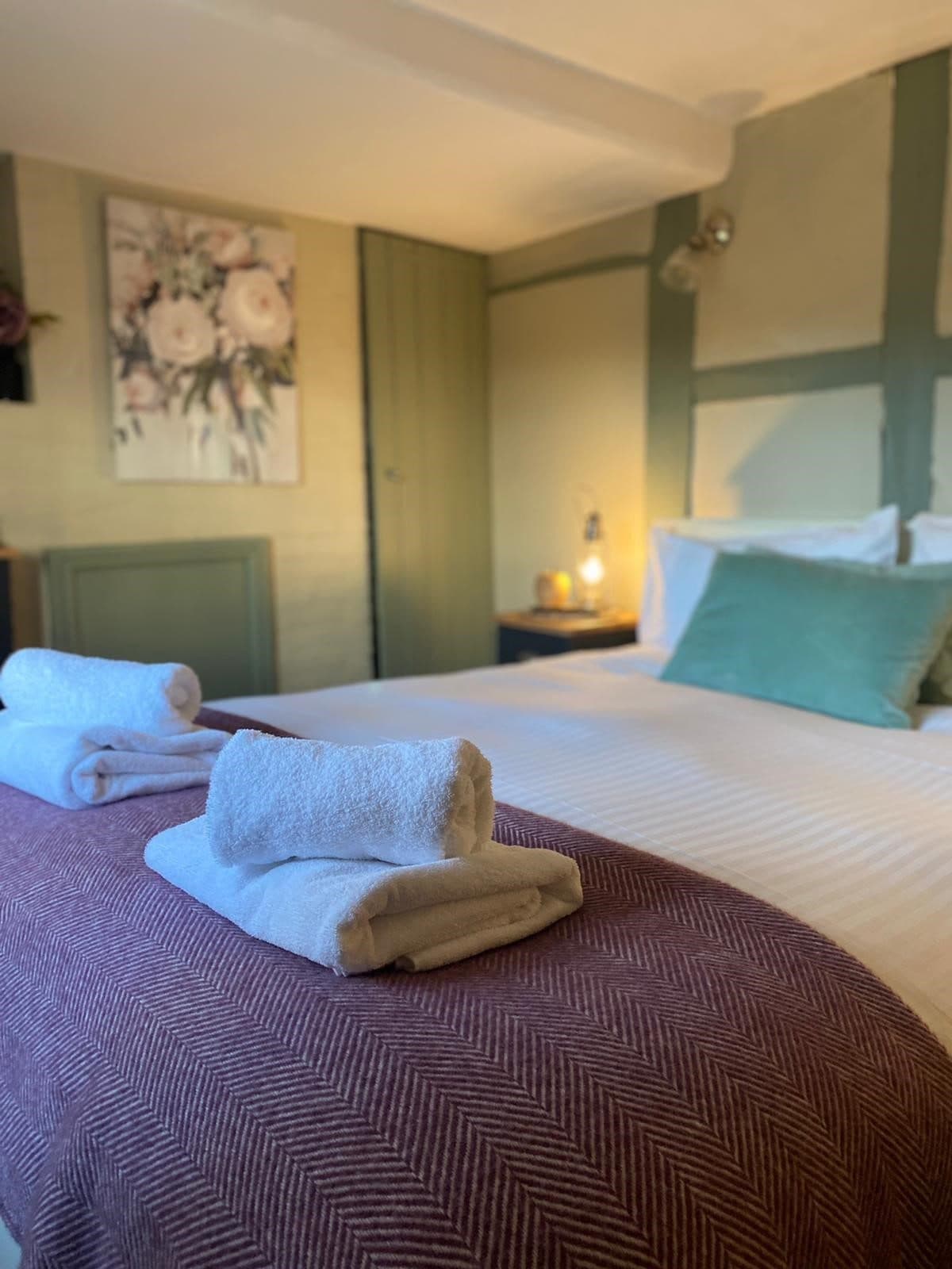 Bedroom with timber details, green beams and rolled towels